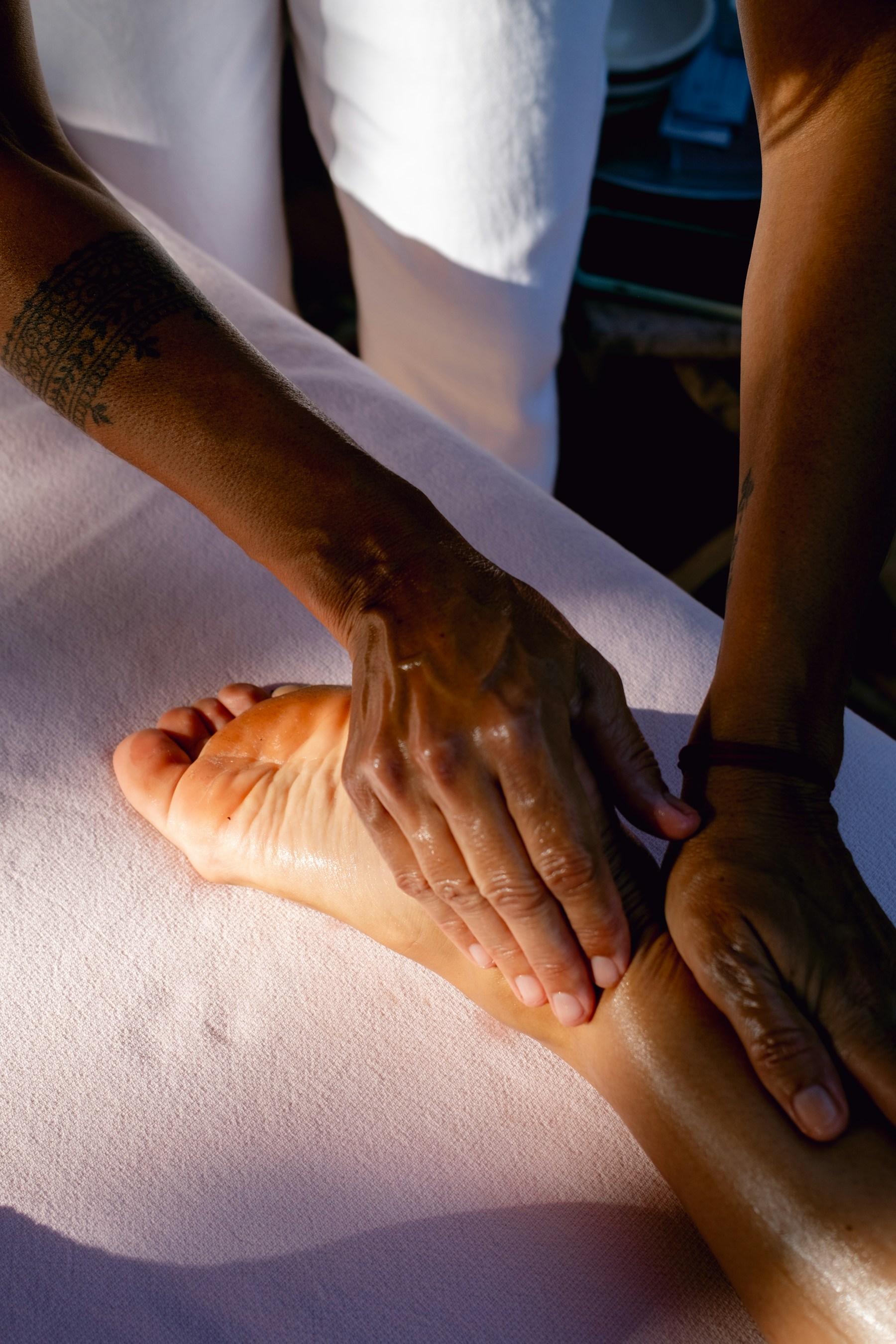 Mains pratiquant un massage du pied sur une table de soin